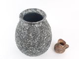 an image of a vase and a small object on a white surface