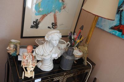 une petite table sur laquelle se trouvent une statue de femme et une poupée