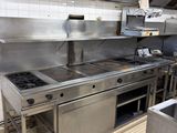 une grande cuisine professionnelle équipée d'appareils électroménagers et de plans de travail en acier inoxydable