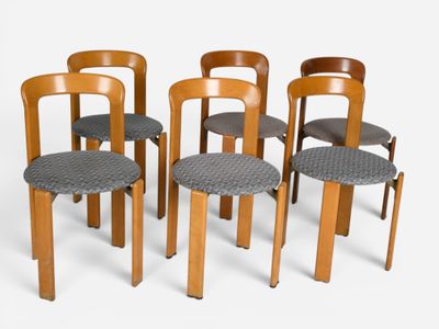 four wooden chairs with grey seat cushions and a white background