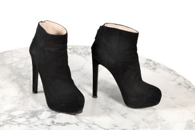 une paire de bottines en daim noir posées sur une table en marbre
