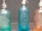 three different colored glass bottles sitting next to each other on a table