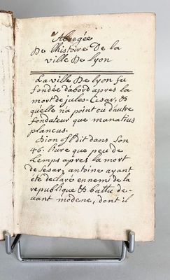 an old book with writing on it sitting on a metal stand