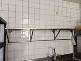 a kitchen with a sink and a metal shelf above the sink