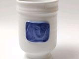 une tasse blanche sur laquelle est dessiné un visage bleu