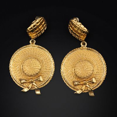 a pair of gold earrings with a circular design and a bow
