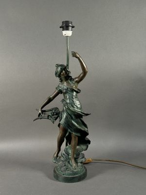 a bronze statue of a woman holding a lamp with a bird in her hand