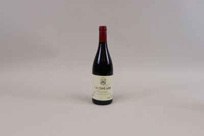 une bouteille de vin rouge posée sur une table blanche