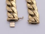 two gold bracelets with a chain attached to them on a white surface