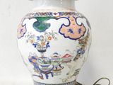 a white and blue vase with a gold base on a table