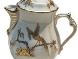 a white tea pot with a gold decoration on it