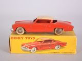 petite voiture miniature dans sa boîte, posée sur une surface blanche avec une boîte jaune