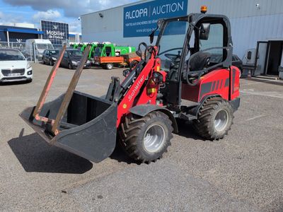 a picture of a red tractor parked in front of a building