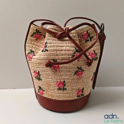 straw bag with pink flowers on it sitting on a white surface