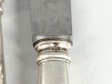pair of silver plated knives on a white surface with a white background