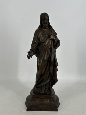 statue en bronze représentant un homme tenant une croix, posée sur un socle