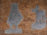 deux figurines en métal représentant un garçon et un chien, posées sur une table en bois