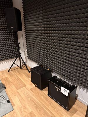 two speakers and a speaker stand in the corner of a room