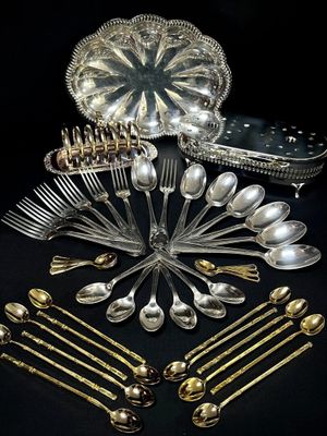 a lot of silverware on a table with a black background