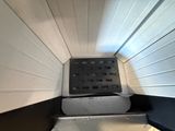 a black and white dog in a kennel with its door open