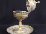 an antique silver plate with a cup and saucer on a black background