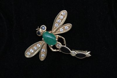 une photo d'une broche en forme de libellule dont les ailes sont ornées de diamants