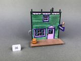 a small green house with a purple door and a sign on the front