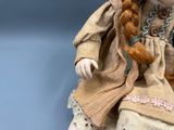 a doll with long red hair sitting on a blue surface