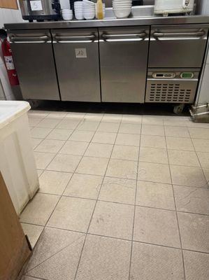 sol carrelé dans une cuisine professionnelle équipée d'appareils électroménagers et de plans de travail en acier inoxydable