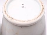a white vase with a brown rim sitting next to a green vase