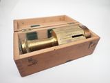 une vieille boîte en bois contenant un télescope, posée sur une surface blanche