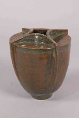 un vase brun posé sur une surface blanche