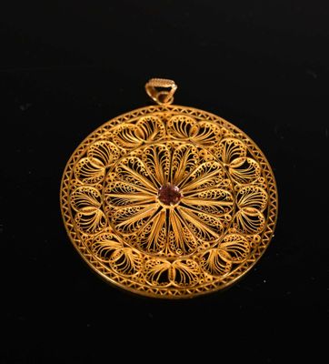 gold filigree pendant with a red stone in the center
