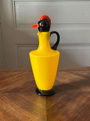 un vase jaune surmonté d'un oiseau noir