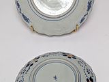 two plates with blue and white designs on them on a white surface