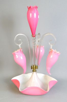 a pink glass vase with flowers on it on a table