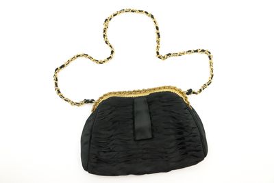 un sac à main noir entouré d'une chaîne dorée, sur fond blanc
