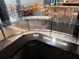 tables and chairs in a restaurant with a curved glass counter