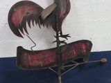 a metal rooster on top of a boat on a pole