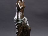 a bronze statue of a woman sitting on top of a table