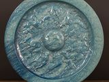 une assiette bleue décorée d'un motif, posée sur un support en bois
