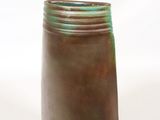 un vase marron et vert posé sur une surface blanche