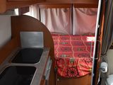 a small kitchen with a sink and a bed in the back of it