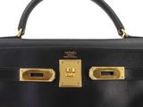 a black leather bag with gold hardware on the handles