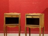 pair of wooden nightstand tables with drawers against a red wall