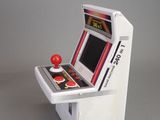 a small toy arcade machine with a red ball on it
