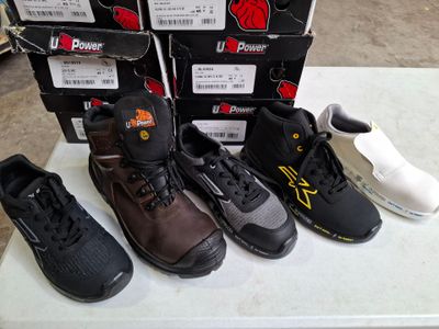 Plusieurs paires de chaussures sont alignées sur une table devant des cartons