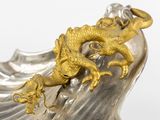 a silver and gold dragon statue on top of a rock