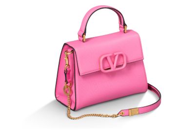 un sac à main rose avec une chaîne dorée sur fond blanc