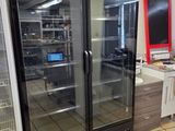 un réfrigérateur au milieu d'une cuisine, avec un ordinateur portable posé sur le plan de travail